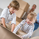 Family moving house and kids packing in boxes